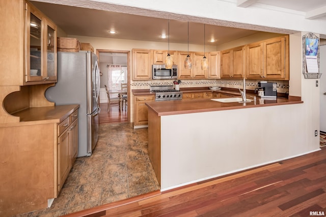 kitchen featuring sink, hanging light fixtures, appliances with stainless steel finishes, tasteful backsplash, and kitchen peninsula