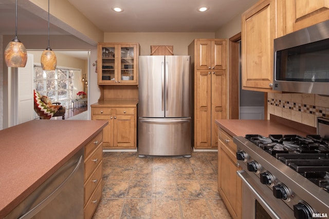 kitchen featuring light brown cabinetry, decorative backsplash, hanging light fixtures, and stainless steel appliances