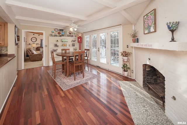 dining area featuring french doors, ceiling fan, beam ceiling, a fireplace, and dark hardwood / wood-style floors