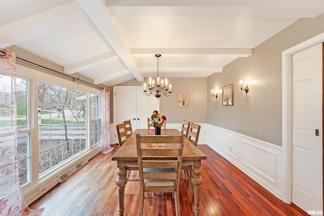 dining space featuring a notable chandelier, lofted ceiling with beams, a decorative wall, hardwood / wood-style flooring, and a wainscoted wall