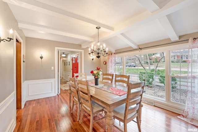 dining space featuring an inviting chandelier, light wood-style flooring, visible vents, wainscoting, and beam ceiling