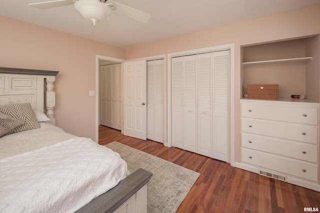 bedroom with ceiling fan, dark wood-type flooring, and two closets