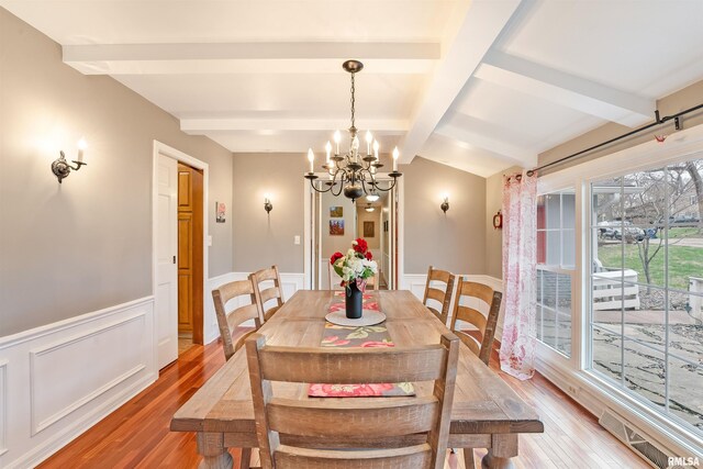 dining space featuring light wood-style flooring, visible vents, a wainscoted wall, and a chandelier