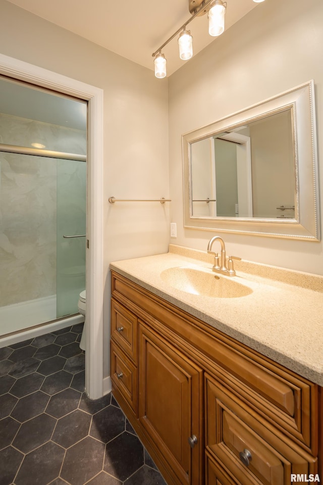 bathroom featuring tile patterned flooring, vanity, toilet, and a shower with shower door