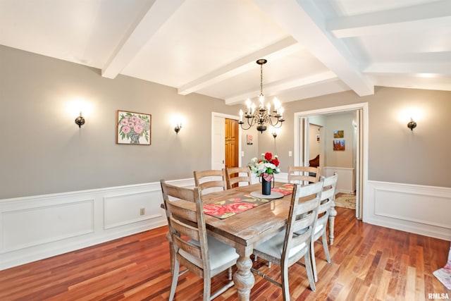 dining room with a chandelier, beamed ceiling, and light wood-style flooring