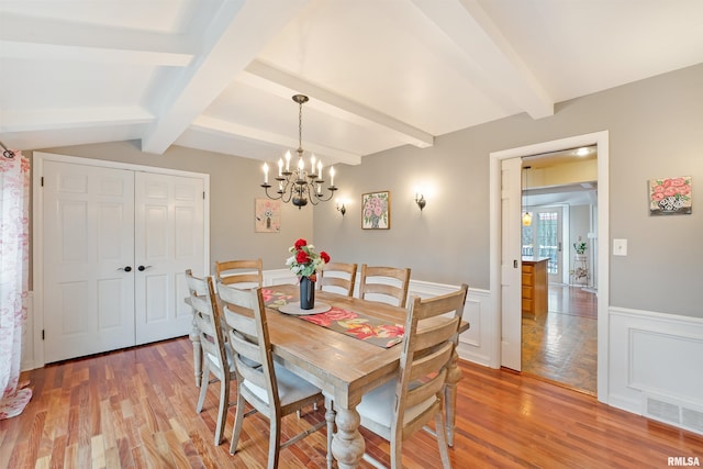 dining area with light wood-style floors, visible vents, an inviting chandelier, and wainscoting