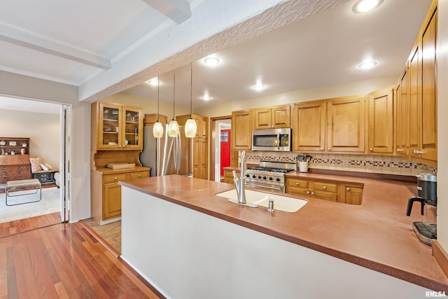 kitchen featuring light wood-style floors, a peninsula, stainless steel appliances, decorative light fixtures, and backsplash