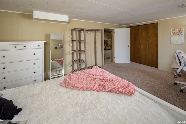 carpeted bedroom featuring a closet and wood walls