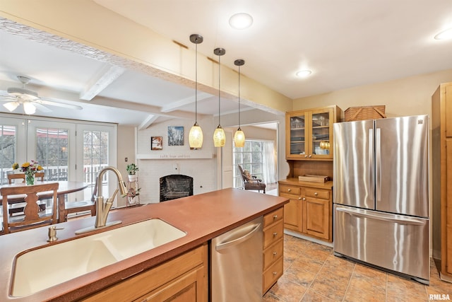 kitchen featuring glass insert cabinets, a brick fireplace, a sink, ceiling fan, and appliances with stainless steel finishes