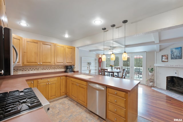 kitchen featuring stainless steel dishwasher, a peninsula, a sink, light countertops, and decorative light fixtures