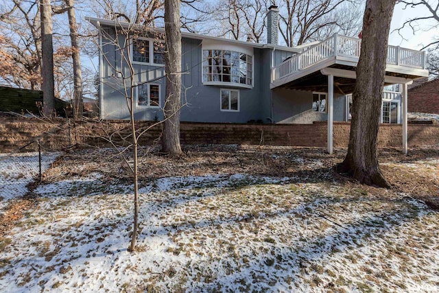 snow covered back of property featuring a deck