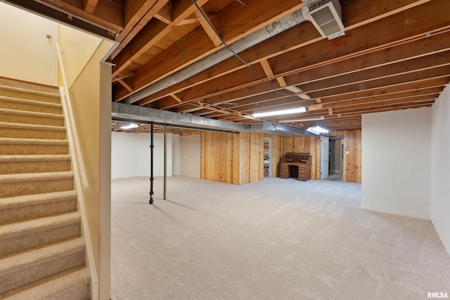 finished basement with stairway, visible vents, and carpet floors