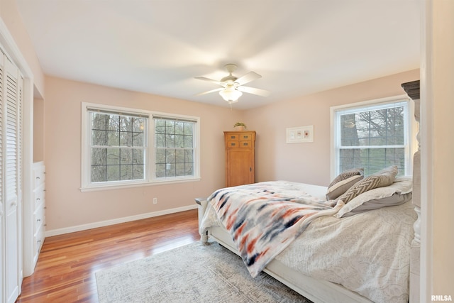 bedroom with light wood-style floors, baseboards, and a ceiling fan