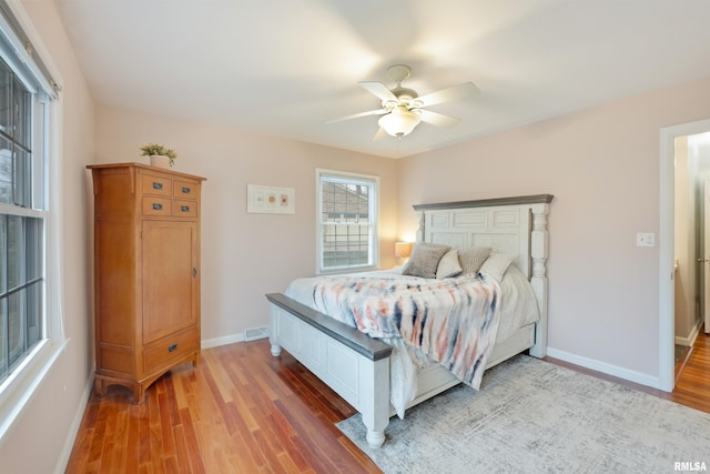 bedroom featuring ceiling fan, light wood finished floors, baseboards, and visible vents