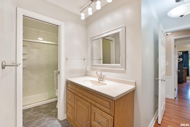 bathroom with a shower stall, vanity, baseboards, and toilet