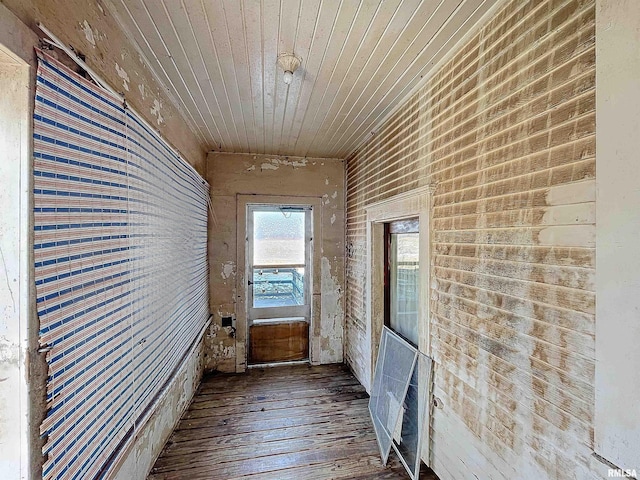 hall with brick wall, hardwood / wood-style floors, and wood ceiling