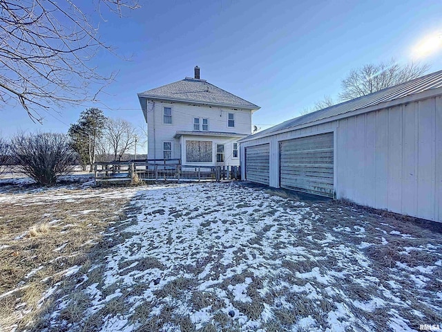 snow covered rear of property featuring an outbuilding