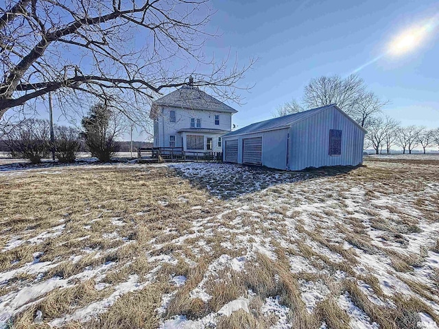 snow covered back of property featuring an outdoor structure