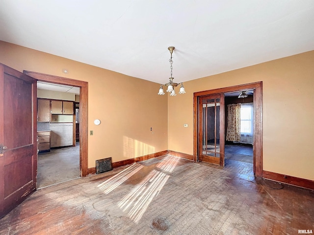 unfurnished room featuring a chandelier