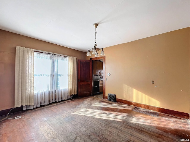 spare room with a chandelier and hardwood / wood-style flooring