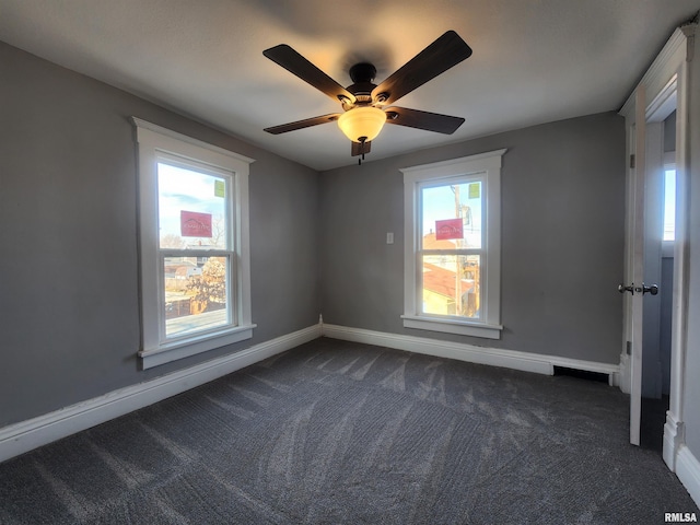 empty room with ceiling fan, plenty of natural light, and dark carpet