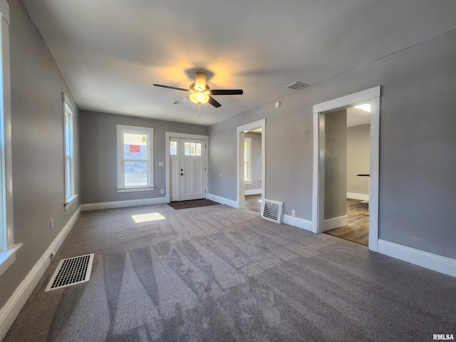 unfurnished room with ceiling fan and dark colored carpet