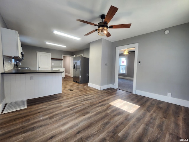 kitchen featuring kitchen peninsula, stainless steel fridge, dark wood-type flooring, sink, and white cabinets