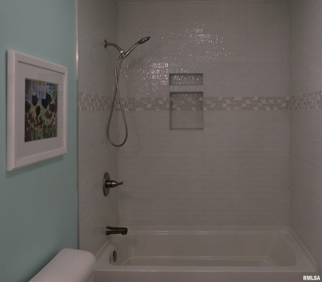 bathroom featuring tiled shower / bath combo and toilet