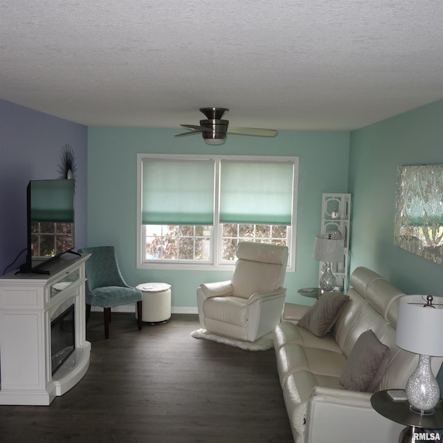 living room featuring ceiling fan, dark wood-type flooring, and a textured ceiling