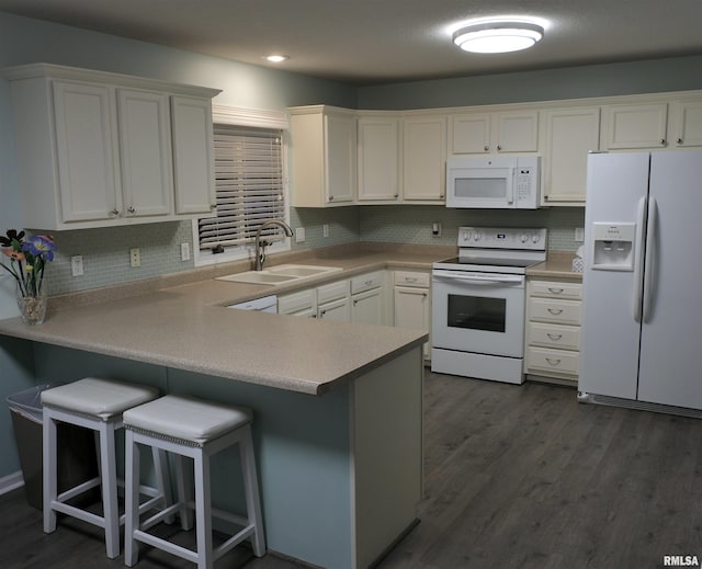 kitchen featuring white appliances, sink, white cabinetry, a kitchen bar, and kitchen peninsula