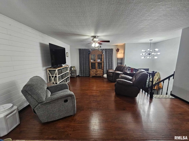 living room featuring dark wood-type flooring, ceiling fan with notable chandelier, and a textured ceiling