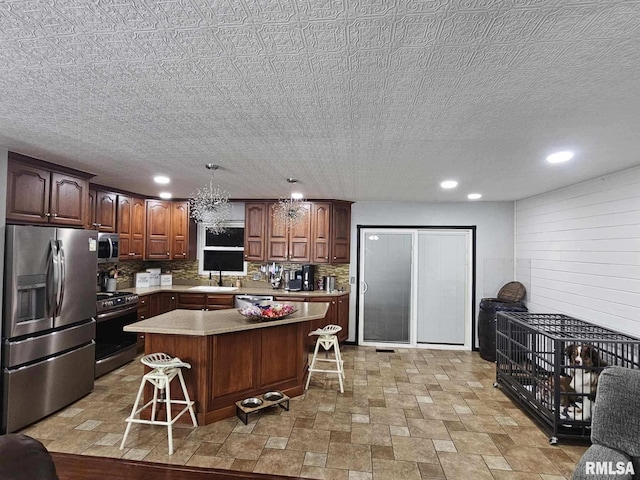 kitchen featuring decorative light fixtures, a kitchen island, stainless steel appliances, and a kitchen bar