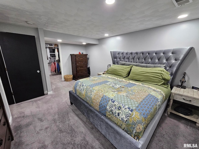 bedroom with carpet floors, a spacious closet, a textured ceiling, and a closet