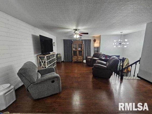 living room with dark hardwood / wood-style flooring, ceiling fan with notable chandelier, and a textured ceiling