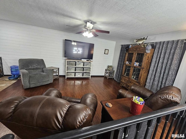 living room featuring ceiling fan, a textured ceiling, and dark hardwood / wood-style flooring