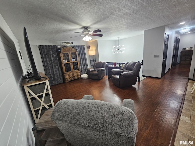 living room with ceiling fan with notable chandelier, a textured ceiling, and dark hardwood / wood-style flooring