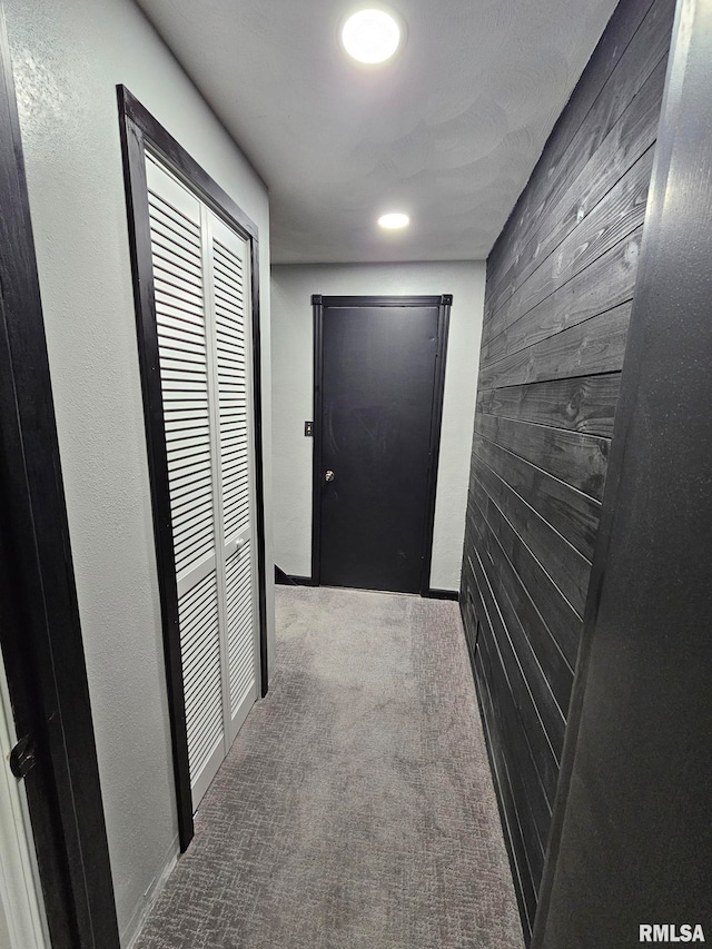 hall featuring carpet flooring and wooden walls