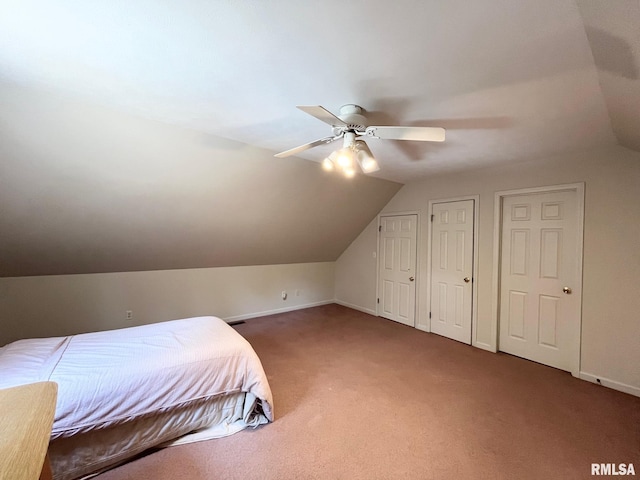 carpeted bedroom with ceiling fan, lofted ceiling, and multiple closets