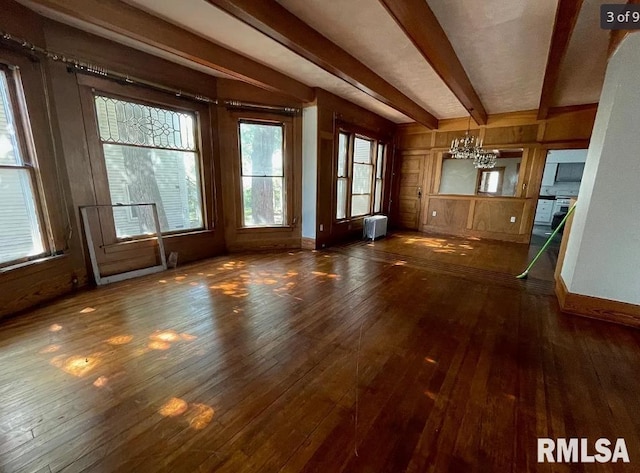 unfurnished living room featuring beam ceiling, radiator heating unit, dark hardwood / wood-style flooring, and a notable chandelier