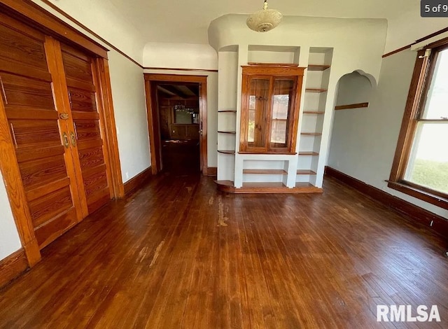 unfurnished living room with built in features and dark hardwood / wood-style floors