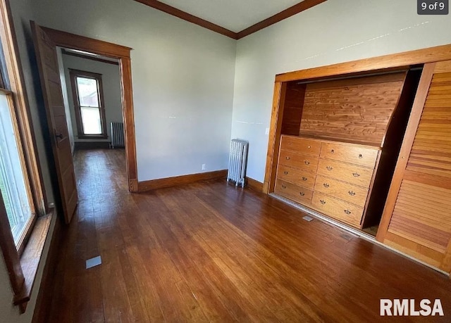 empty room featuring radiator heating unit, dark hardwood / wood-style floors, and crown molding