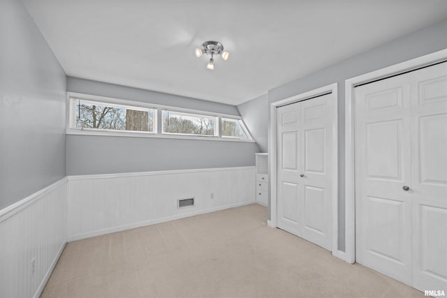 unfurnished bedroom with light colored carpet and multiple closets