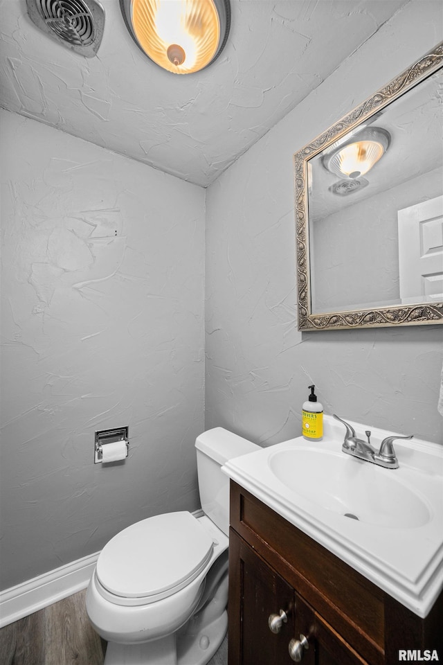 bathroom with wood-type flooring, vanity, and toilet