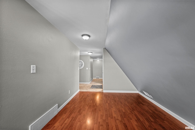 corridor featuring wood-type flooring and vaulted ceiling