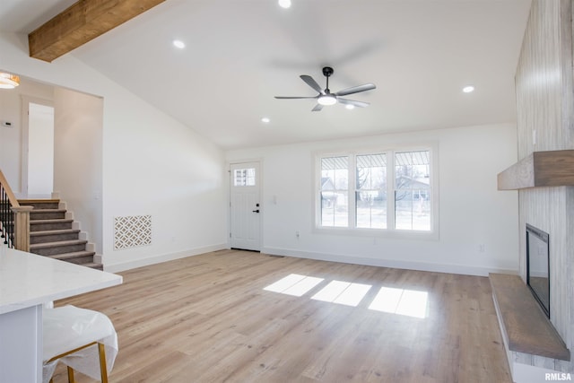 unfurnished living room with light hardwood / wood-style floors, plenty of natural light, ceiling fan, and vaulted ceiling with beams