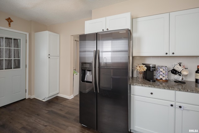 kitchen featuring white cabinets, stainless steel refrigerator with ice dispenser, and dark stone counters