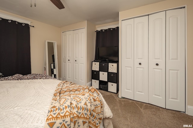 carpeted bedroom with ceiling fan and two closets