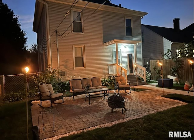 back house at dusk with a patio and an outdoor living space with a fire pit