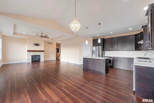 kitchen featuring sink, hanging light fixtures, stainless steel appliances, backsplash, and a kitchen island