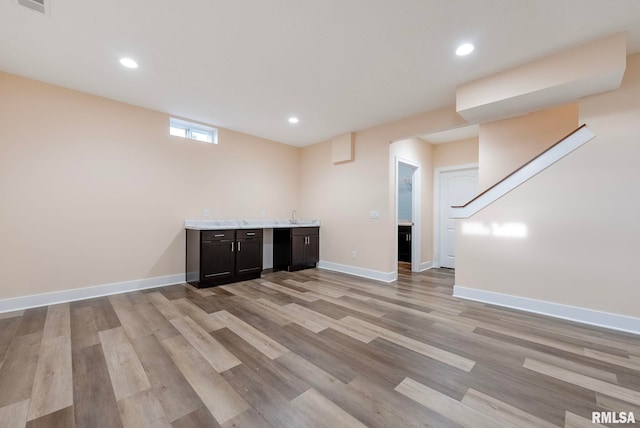 basement featuring sink and light hardwood / wood-style flooring